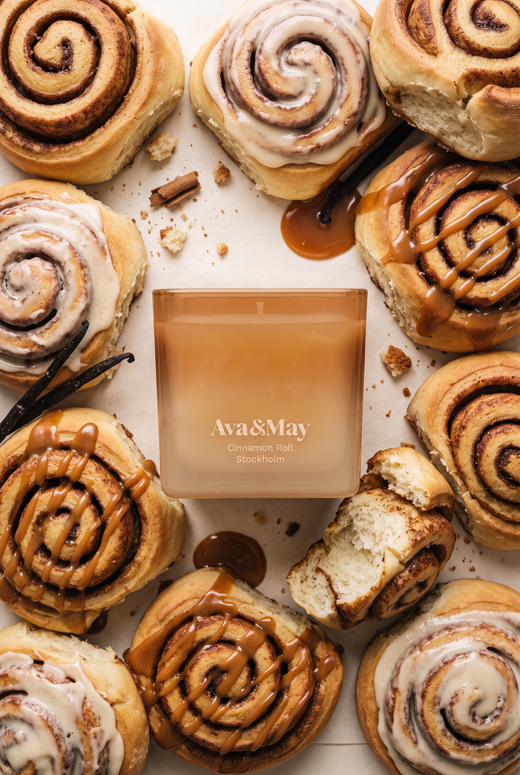 La candela Cinnamon Roll di Ava&May distesa e circondata da tanti dolcetti alla cannella con vaniglia e crema al caramello