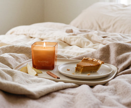 Candela Pumpkin Pie 220g di Ava&May accesa su un vassoio posato su un letto con fetta di torta con crema alla zucca, pere e cannella